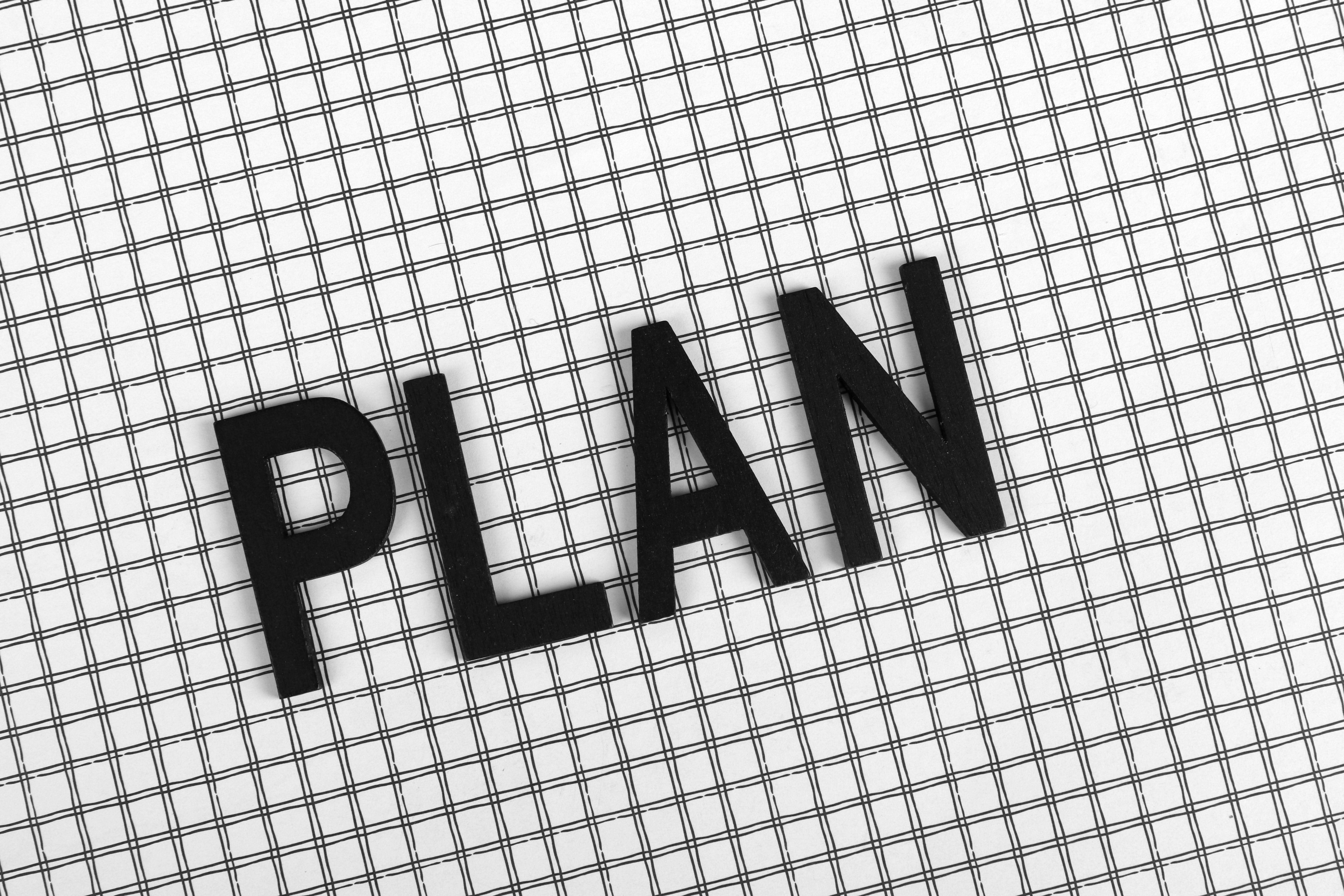 La palabra PLAN formada con letras negras sobre una hoja de papel cuadriculado.